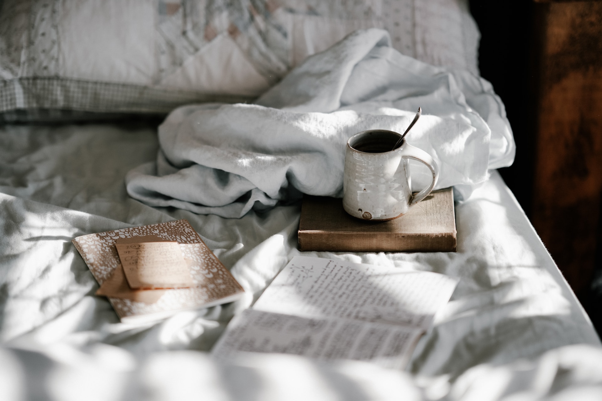 Journaling with a hot mug in a cozy bed. Image by Annie Spratt
